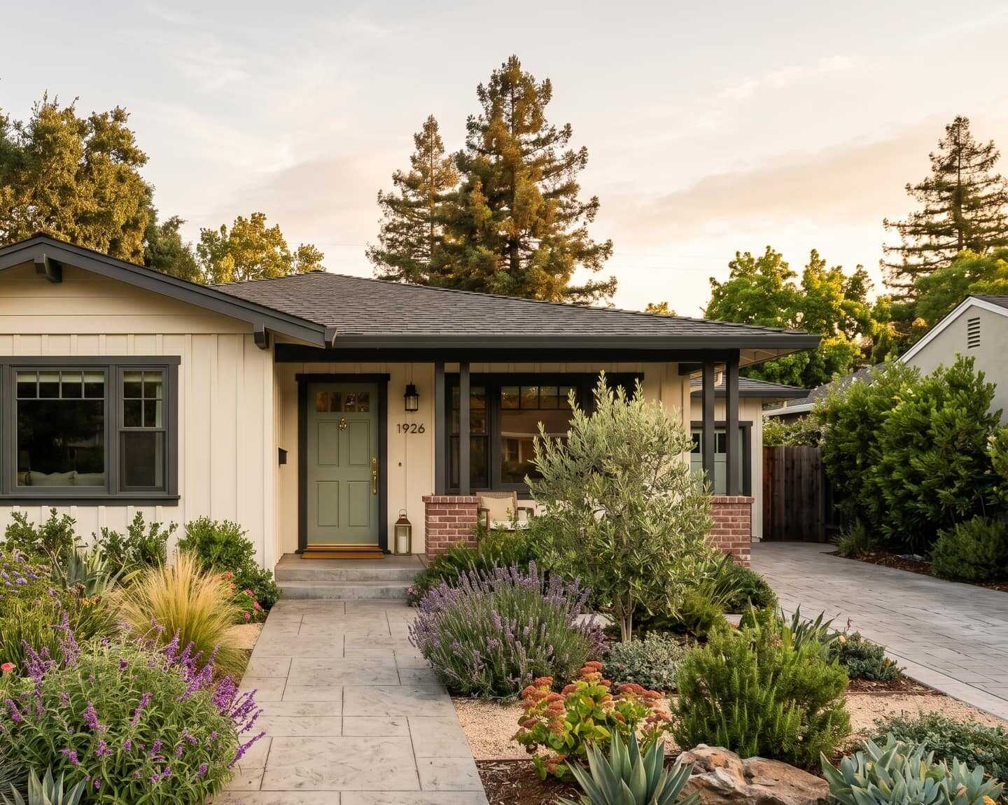 Single-story board-and-batten ranch home with dark trim, a sage front door, and drought-tolerant landscaping in evening light.