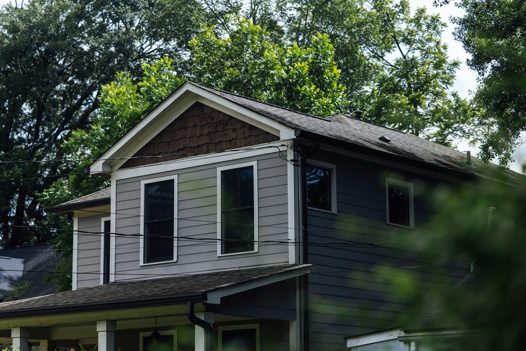 Gray two-story home with a gabled front and new gutters along the eaves.