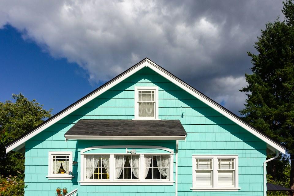 Freshly painted teal shingle siding with crisp white window trim on a gable end.