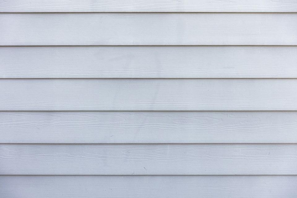 Close view of white horizontal lap siding in even, straight courses.
