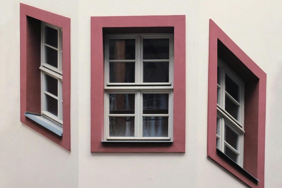 Three white sash windows with painted trim on a light exterior wall.